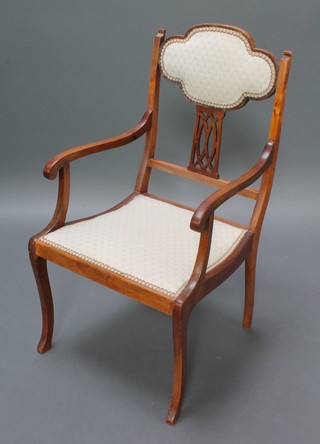 An Edwardian bleached mahogany open arm chair with upholstered seat and back raised on shaped supports 