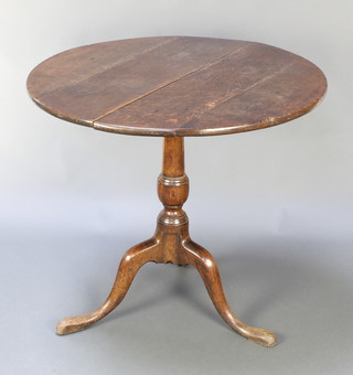 An 18th Century oak circular snap top tea table, raised on pillar and tripod base 29"h x 32"