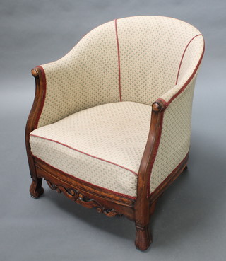 A 1930's mahogany show frame tub back chair upholstered in cream material with carved and pierced apron, raised on carved supports 

