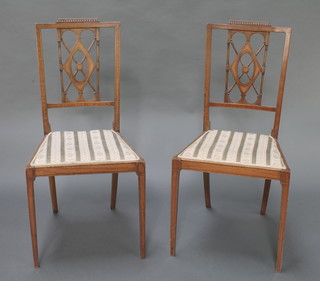 A pair of Edwardian inlaid mahogany rail back bedroom chairs with upholstered seats, raised on square tapered supports 