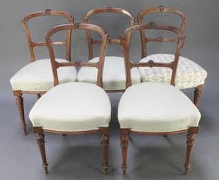 A set of 5 Victorian carved walnut rail back dining chairs with carved mid rails and upholstered seats, on turned and fluted supports 