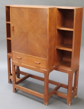 A Heales style light oak breakfront cabinet enclosed by a quarter panelled door flanked by shelves above 1 long drawer, raised on square tapering supports 45"h x 39"w x 15"d 
