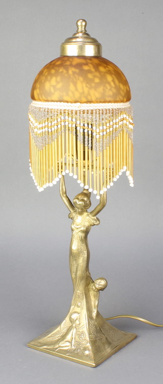 An Art Nouveau style gilt metal table lamp in the form of a standing lady with arms outreached and with an amber glass shade 20" 