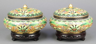 A pair of Chinese circular squat cloisonne enamelled jars and covers raised on pierced hardwood stands 6" 