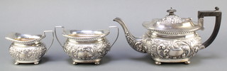 A Victorian repousse silver 3 piece tea set with armorial decoration, comprising teapot with ebonised wooden handle, twin handled sugar bowl and milk jug, Birmingham 1899 by Joseph Gloster,  gross weight 1086 grams