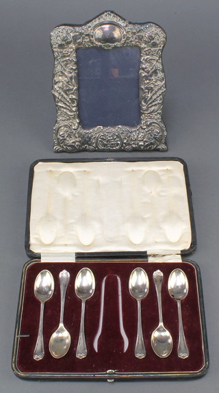 A repousse silver photograph frame with cavorting cherubs Birmingham 1993 7 1/2" together with a cased set of 6 silver teaspoons, Sheffield 1918, 72 grams 
