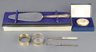 2 silver napkin rings 1913 and 1924, 34 grams, a silver handled cake slice, ditto fruit knife, swizzle stick and a Halcyon days enamelled box 
