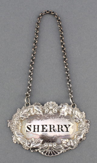 A Georgian silver sherry label with repousse decoration 