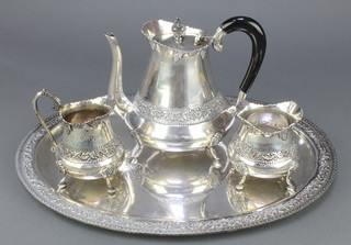 A Persian white metal 3 piece tea set with repousse floral and vinous decoration together with an oval tray 