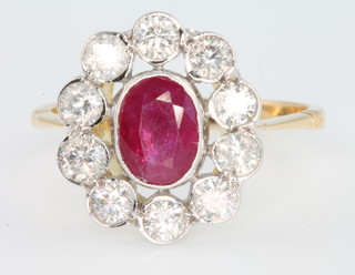 An 18ct yellow gold oval ruby and diamond cluster ring, the centre stone approx. 1.20ct surrounded by 10 brilliant cut diamonds approx. 0.95ct, size N 1/2