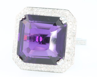 A 14ct white gold amethyst and diamond cocktail ring, the square cut centre stone approx. 13ct surrounded by a 2 tier brilliant cut diamond set mount with diamonds to the shoulders, size M 1/2