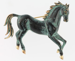 A stylish bronzed and gold horse brooch 