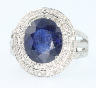 A 14ct white gold oval sapphire and diamond cocktail ring, the centre stone approx. 6.75ct surrounded by brilliant cut diamonds, approx 1.1ct size M 1/2 
