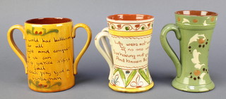 A Devon Ware waisted 2 handled mug with motto 1821 6", 1 other -  6" (slight chip to rim) and 1 other Devon twin handled mug with motto (cracked) 
