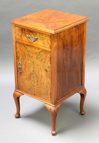 An Art Deco walnut bedside cabinet fitted a drawer above a panelled door, raised on cabriole supports 30"h x 15 1/2" square 