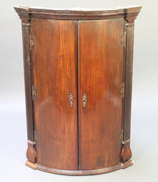 A Georgian mahogany hanging corner cabinet with moulded cornice and fluted columns to the side, fitted shelves enclosed by panelled door 41"h x 30"w x 20"d 