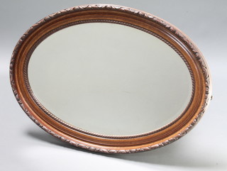 An oval bevelled plate wall mirror contained in a decorative carved mahogany frame 34" x 24 1/2"