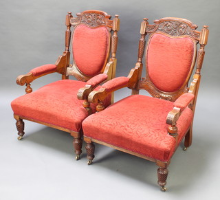 A pair of early Victorian carved mahogany show frame open arm chairs upholstered in red sculptured material raised on turned and fluted supports