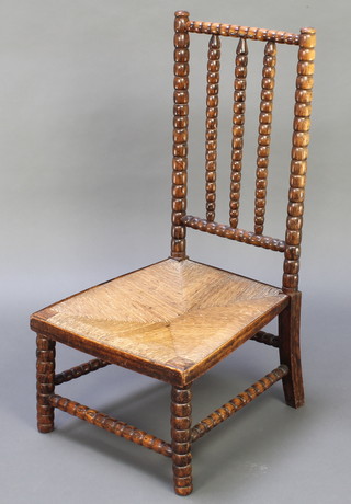 An elm bobbin turned stick and rail back nursing chair with woven rush seat