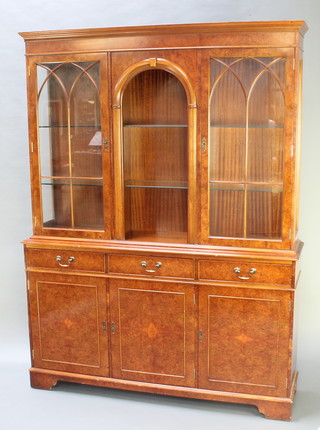 A Georgian style figured walnut display cabinet, the upper section with moulded cornice fitted a recess flanked by 2 cupboards enclosed by astragal glazed panelled doors, the base fitted 3 drawers above a triple cupboard, raised on bracket feet 77"h x 57 1/2"w x 14 1/2"d 