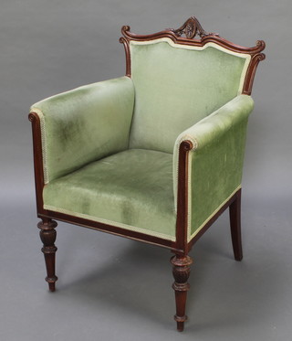 An Edwardian mahogany show frame armchair upholstered in green Dralon and raised on turned supports 