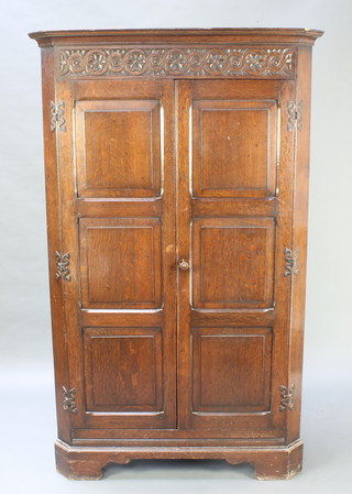 A Victorian carved oak corner cabinet with moulded cornice enclosed by panelled doors with stylised H framed hinges, raised on bracket feet 73"h x 45"w x 26"d 