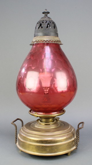 A twin handled brass oil lamp with red glass shade converted for use as an electric table lamp 
