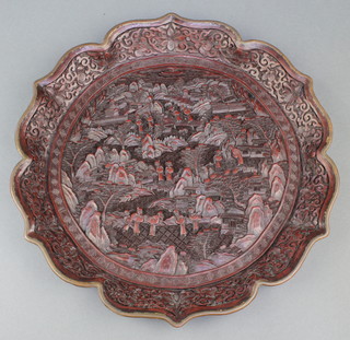 A Chinese carved cinnabar lacquer dish decorated figures in landscape with metal edge bracketed border, the reverse set a metal seal mark 13" diam. 