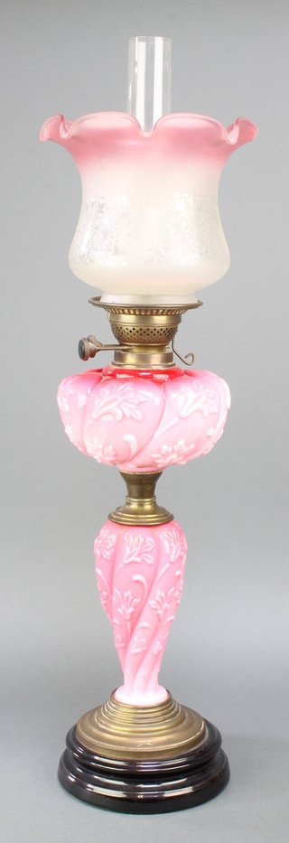 A Victorian opaque pink glass oil lamp with gilt metal mounts, etched pink shade and clear glass chimney 