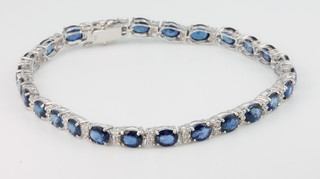 An 18ct white gold sapphire and diamond bracelet, comprising 26 oval cut sapphires interspersed with brilliant cut diamonds, sapphires 13.6ct, diamonds 0.47ct 