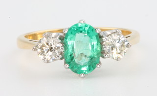 An 18ct yellow gold emerald and diamond 3 stone ring, the centre stone 1.1ct flanked by 2 brilliant cut diamonds 0.52ct, size M 1/2