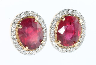 A pair of yellow gold oval ruby and diamond cluster ear studs, the centre stones approx. 4.56ct surrounded by brilliant cut diamonds approx. 0.37ct 