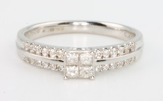 An 18ct white gold diamond ring with 4 princess cut stones and 24 channel set brilliant cut diamonds, size N 