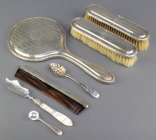 A silver brush set with engine turned decoration comprising hand mirror and 2 clothes brushes, a ditto comb, 2 spoons and a butter knife