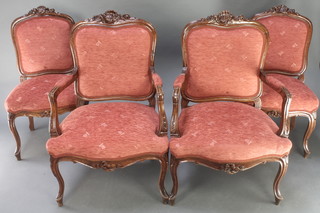 A pair of Continental heavily carved walnut armchairs and a pair of standard chairs with shell carved crest, upholstered in orange material, on cabriole supports 
