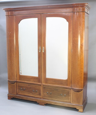 An Edwardian inlaid mahogany wardrobe with moulded shaped cornice, enclosed by a pair of arched bevelled plate panelled doors, the base fitted 2 drawers flanked by 2 small cupboards, raised on bracket feet 84"h x 82"w x 23"d 