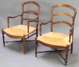 A pair of 19th Century French elm ladder back open arm chairs with woven rush seats and X framed stretchers, raised on turned supports 