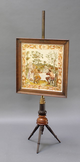 A 19th Century mahogany and brass pole screen with stitch work banner depicting a feasting scene contained in an oak frame and raised on turned and fluted mahogany base 