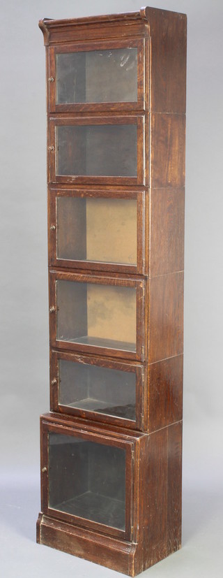 An oak Globe Wernicke style 6 tier bookcase enclosed by panelled doors, raised on a platform base 77"h x 18 1/2"w x 12"d 