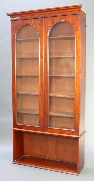 A Victorian mahogany bookcase, the upper section with moulded cornice, the interior fitted adjustable  shelves enclosed by arched panelled doors, the base fitted a recess 80 1/2"h x 41"w x 11"d 
 