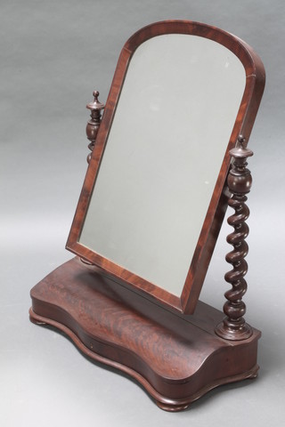 A Victorian arched plate dressing table mirror contained in a mahogany frame with spiral turned columns to the side, the base of serpentine outline fitted a glove box, raised on bun feet 36"h x 28"w x 12"d 
