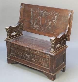 A carved oak monks bench with hinged lid and carved lion mask arms 27"h x 41"w x 19"d 