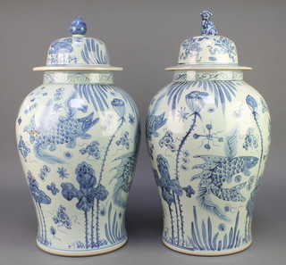 A pair of Chinese blue and white baluster jars and covers decorated with carp amongst seaweed 23" 