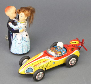 A Japanese tin plate model racing car, prop-rod and 1 other figure of a dancing couple 