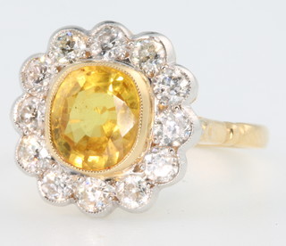 An 18ct yellow gold yellow sapphire and diamond cluster ring, the centre stone surrounded by 12 brilliant cut diamonds, size O 