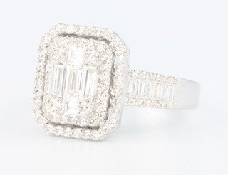 A white gold diamond cocktail ring with 5 baguettes surrounded by 2 tiers of brilliant cut diamonds, the shank with 6 baguettes and brilliant cut diamonds to each shoulder, approx. 1.3ct, size M 1/2
