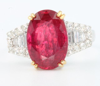 An 18ct yellow gold ruby and diamond ring, the oval centre stone (treated) flanked by baguette and brilliant cut diamonds, size N