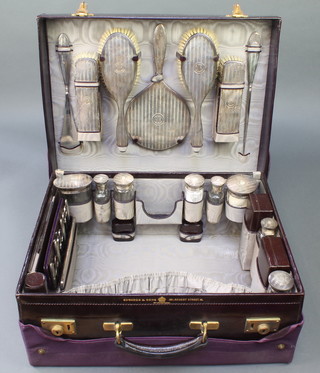 A leather case containing a 7 piece silver brush set and 8 silver mounted jars together with a comb and a manicure set with cover