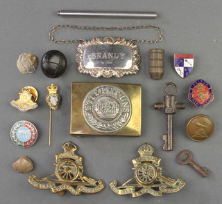 A Royal Artillery cap badge, minor cap badges etc including a silver spirit label 
