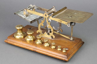 A pair of 19th Century brass letter scales raised on a mahogany stand with 7 weights - 1lb, 8 ozs, 4 ozs, 2 ozs, 1 oz, 1/2 oz, 1/4 oz, 